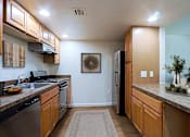 Thumbnail 5 of 20 - A kitchen with wooden cabinets and a black refrigerator.