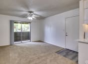 Thumbnail 8 of 17 - an empty living room with a door to a balcony and a ceiling fan