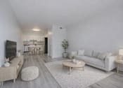Thumbnail 1 of 18 - A modern living room with a white couch, wooden coffee table, and a television.