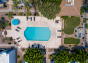 Thumbnail 5 of 15 - An aerial view of a swimming pool surrounded by trees and buildings.
