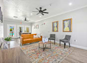Thumbnail 13 of 17 - A living room with a yellow couch, two chairs, and a coffee table.