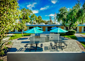 Thumbnail 14 of 14 - A patio with tables and chairs under blue umbrellas. at The Link Apartments, Mesa, Arizona