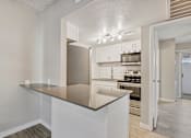 Thumbnail 2 of 12 - A kitchen with a stainless steel refrigerator and white cabinets at Tides on East Cactus Apartments, Phoenix, AZ, 85032