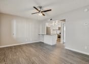 Thumbnail 4 of 12 - A spacious room with a ceiling fan and light fixture, and a kitchen area visible through the open door at Tides on East Cactus Apartments, Phoenix, Arizona
