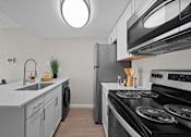 Thumbnail 6 of 28 - A modern kitchen with a black stove top oven and a white countertop  at Tides on McDowell, Phoenix, 85035