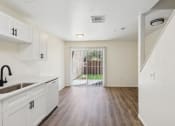 Thumbnail 3 of 15 - the living room and kitchen of an apartment with white cabinets and wood flooring