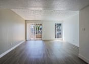 Thumbnail 38 of 94 - A spacious room with wooden floors and a view of a balcony through the windows.