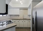 Thumbnail 43 of 94 - A modern kitchen with white cabinets and a stainless steel refrigerator.