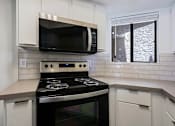 Thumbnail 40 of 94 - A modern kitchen with a black stove top oven and white cabinets.
