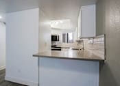 Thumbnail 37 of 94 - A modern kitchen with a stainless steel counter and white cabinets.