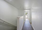 Thumbnail 36 of 94 - A long hallway with a white wall and a white door.