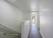 Thumbnail 19 of 51 - A hallway with a staircase and a door at the end.