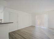 Thumbnail 8 of 32 - an empty living room and kitchen with white walls and wood flooring