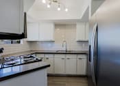 Thumbnail 20 of 94 - A modern kitchen with white cabinets and a black countertop.