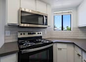 Thumbnail 19 of 94 - A modern kitchen with a stove and microwave.