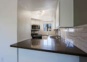 Thumbnail 17 of 94 - A kitchen with a black counter top and white cabinets.