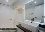 Thumbnail 5 of 51 - A bathroom with a backlit sink and tile tub and shower.
