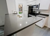 Thumbnail 16 of 32 - a kitchen with white cabinets and a black counter top