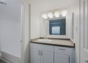 Thumbnail 22 of 32 - a bathroom with a sink and a mirror and a shower