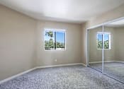 Thumbnail 12 of 94 - A room with a carpeted floor and a sliding glass door leading to a balcony.
