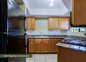 Thumbnail 24 of 51 - A kitchen with a black refrigerator and wooden cabinets.