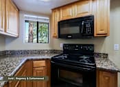 Thumbnail 25 of 51 - A black microwave is mounted above a black stove in a kitchen with wooden cabinets.
