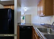 Thumbnail 28 of 51 - A black fridge in a kitchen with wooden cabinets.