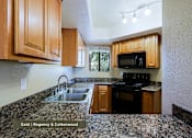 Thumbnail 23 of 51 - A kitchen with wooden cabinets and a granite countertop.