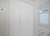 Thumbnail 9 of 19 - A white cabinet with a digital clock on the wall above it.
