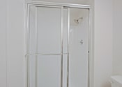 Thumbnail 13 of 19 - A white bathroom with a glass door shower enclosure.
