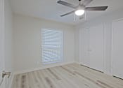 Thumbnail 10 of 19 - A room with a ceiling fan and wooden flooring.