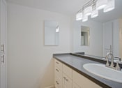 Thumbnail 19 of 36 - A bathroom with a sink and mirror.