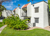 Thumbnail 3 of 16 - A white stucco building with a red tile roof and a balcony.