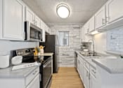 Thumbnail 5 of 16 - A kitchen with white cabinets and a black refrigerator.