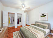 Thumbnail 7 of 21 - A bedroom with a bed, a ceiling fan, and a wardrobe with clothes hanging.