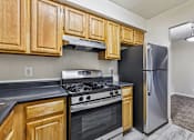 Thumbnail 2 of 43 - A kitchen with wooden cabinets and a black refrigerator.