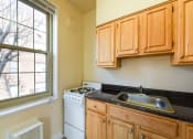 Thumbnail 7 of 19 - kitchen with gas range, wood cabinetry and large window  at 1401 sheridan apartments in washington dc