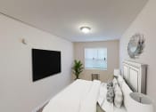 Thumbnail 6 of 15 - bedroom with bed, nightstand, tv and windows at manor village  tax credit apartments in washington dc