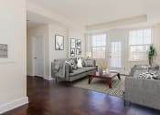 Thumbnail 8 of 21 - living area with large windows, patio door, sofa, coffee table and hardwood flooring at juniper apartments in washington dc