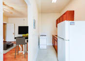 Thumbnail 5 of 15 - kitchen with wood cabinetry, gas range, refrigerator and view of living area at 1818 riggs apartments in washington dc