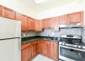 Thumbnail 1 of 28 - kitchen with wood cabinetry, stainless steel appliances and tile backsplash at the norwood apartments in adams morgan washington dc