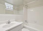Thumbnail 8 of 17 - A white bathroom with a sink, tub, and window.