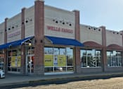 Thumbnail 22 of 24 - A Wells Fargo bank with a blue awning and a white car parked in front.