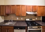 Thumbnail 1 of 26 - kitchen with dark wood cabinetry, gas range and tile backsplash  at 2800 ontario road apartments in washington dc