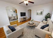 Thumbnail 3 of 16 - A living room with a beige couch, a coffee table, and a television.
