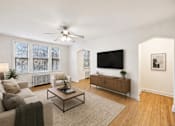Thumbnail 1 of 21 - A living room with a couch, a coffee table, and a flat screen TV.