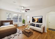 Thumbnail 3 of 21 - A bedroom with a brown bed and a white couch with a painting on the wall.