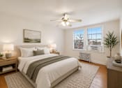 Thumbnail 2 of 21 - A bedroom with a large bed, a ceiling fan, and a window with a view of a cityscape.