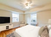 Thumbnail 16 of 18 - bedroom with bed, dresser, tv, seating area with windows and ceiling fan at 4031 davis place apartments in washington dc
