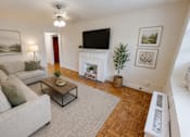 Thumbnail 2 of 19 - A living room with a grey couch, a coffee table, a fireplace, and a painting on the wall.